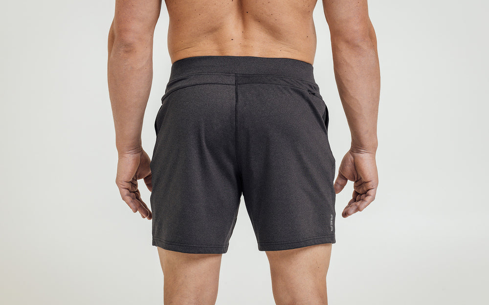 Back view of model wearing the heather black REP Versa Shorts.
