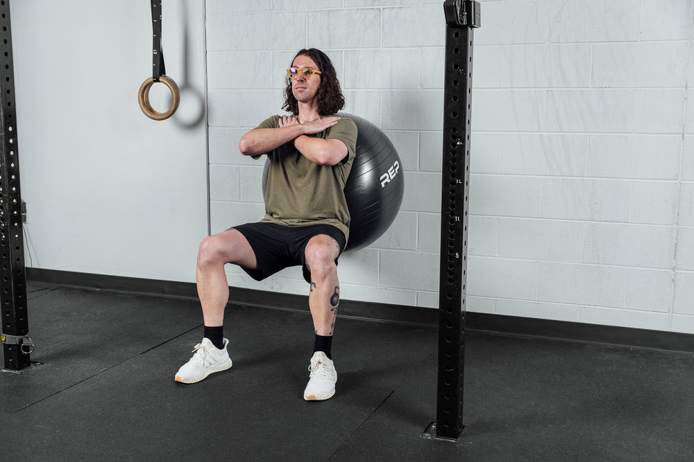 A wider shot of an athlete performing wall squats on the Physioball.