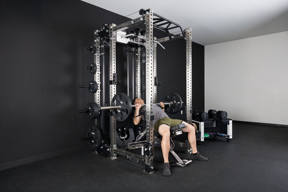 An athlete incline bench pressing inside the PR-5000 rack on a BlackWing adjustable bench