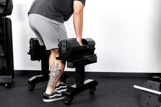Athlete prepares to stand with adjustable dumbbells.
