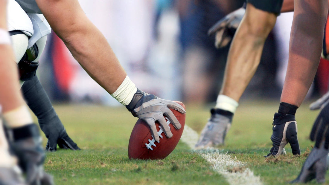 Football player's hand on a football at the line of scrimmage