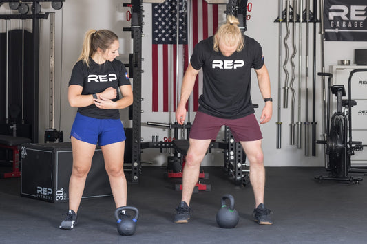 A personal trainer instructs her client in a home gym.