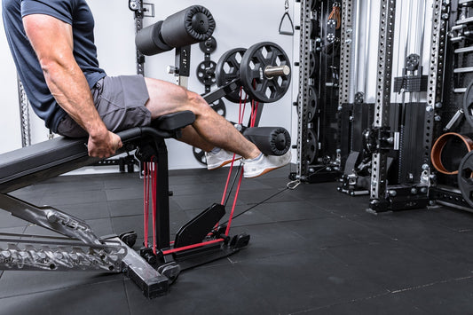 A man performs a leg extension using a leg curl / leg extension machine.