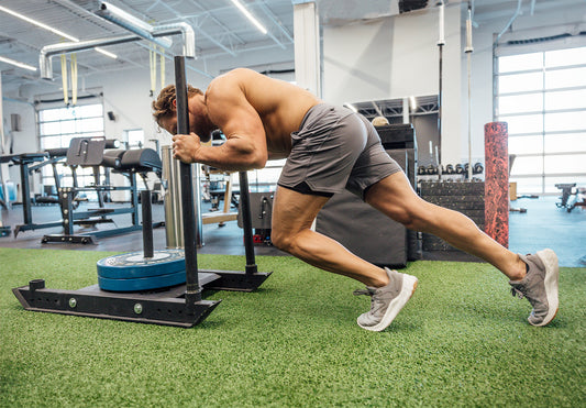 Men pushing sled in REP shorts