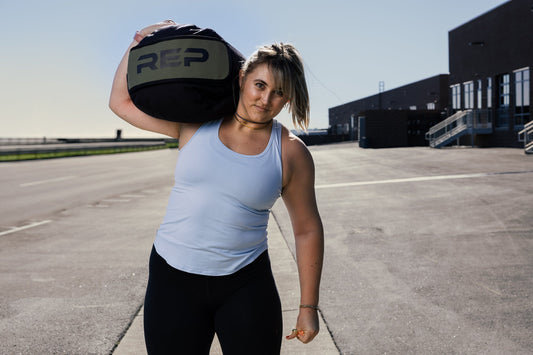 Athlete carries REP® Stone Sandbag over one