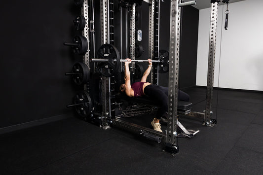 An athlete tackles a bench press with the REP® Smith Machine attachment.