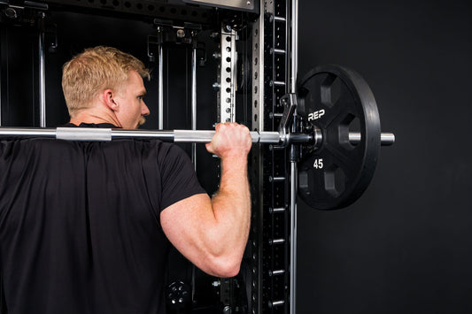 An athlete unracks the bar on the REP® Smith Machine attachment.