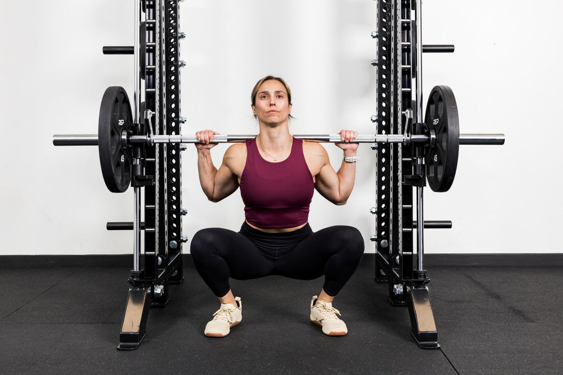 Front view of a woman doing a Smith machine squat with the REP® Smith Machine attachment.