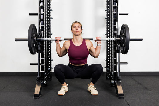 Front view of a woman doing a Smith machine squat with the REP® Smith Machine attachment.