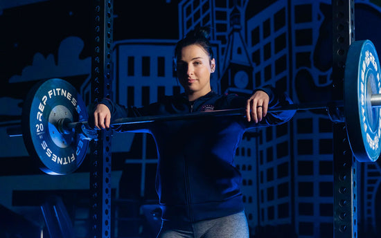 Woman resting with her hands on a barbell