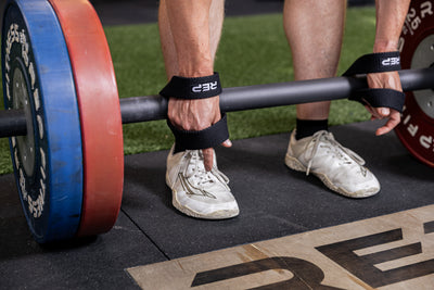 Athlete putting on the REP Fitness figure 8 lifting straps
