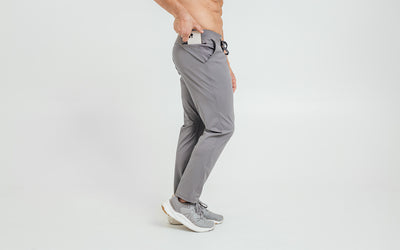 Model sliding his iPhone into the side hip pocket of the cool gray REP Felix Pants
