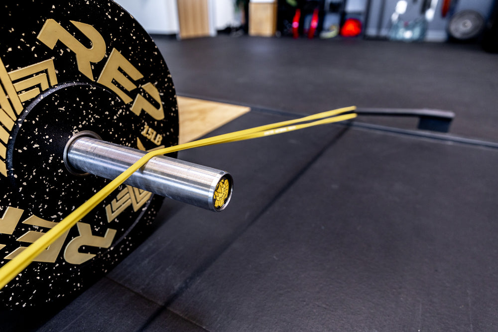 Close-up view of a yellow Latex-Free Pull-Up Band being used for added resistance while deadlifting.