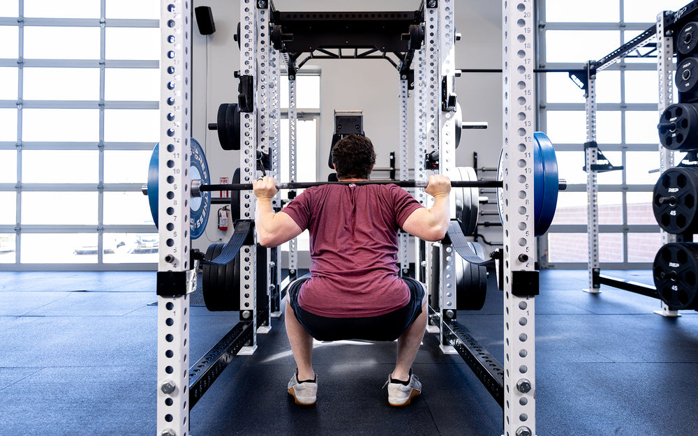 Person squatting with Colorado Short Bar inside a rack