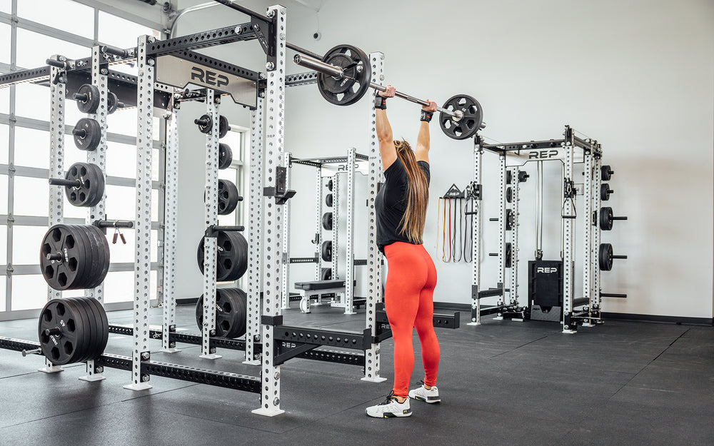 Female lifter with a loaded REP Double Black Diamond Power Bar in the overhead position.