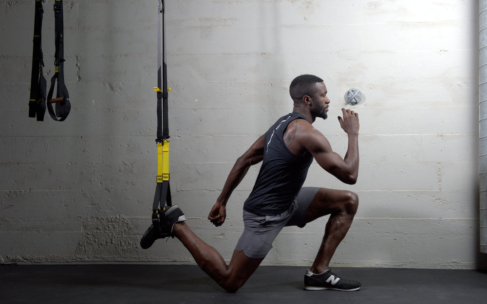 Action shot: Athlete performing split squats utilizing the foot cradle on the TRX® CLUB4