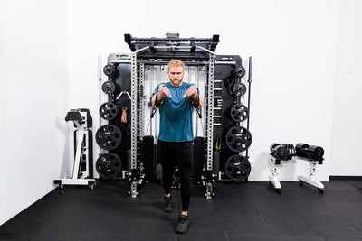 Person using the Ares™ 2.0 for cable machine exercises on the Summit™ All-In-One Ares™ 2.0 Wall-Mounted configuration in a gym setting.