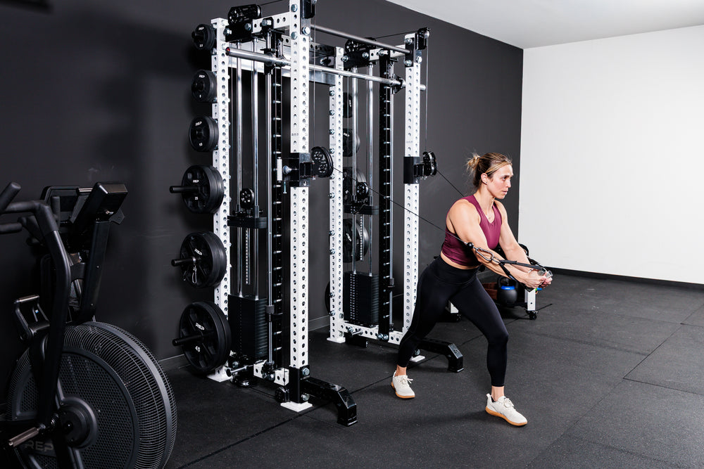 Women performing cable machine exercises on the Summit™ All-In-One Trainer with Athena™in a home gym setting.