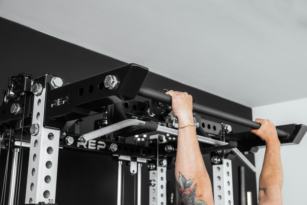 Person performing pull-ups on a pull-up bar (Ares 2.0 4-Post Pull-Up Bar + Pull-Up Bar Extension Brackets).