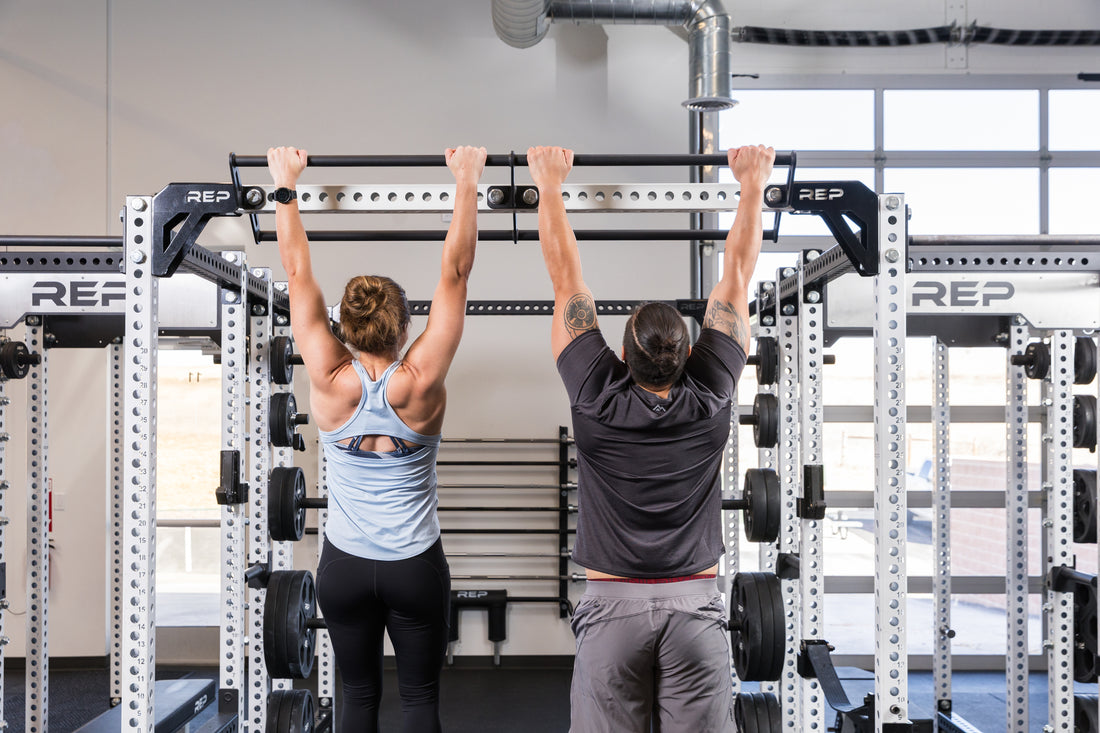 Two athletes hanging from the REP Fitness Double Pull-Up Bar on an 82 inch crossmember