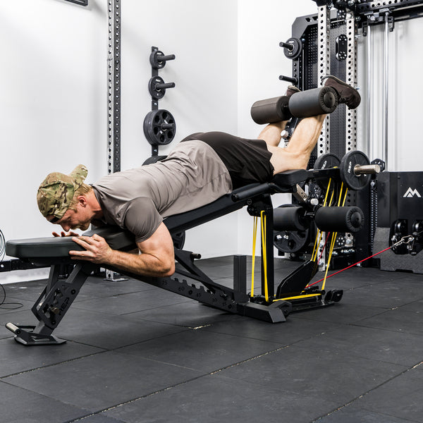 Athlete using resistance bands, weight plates, and cable resistance on the Leg Extension & Leg Curl Bench Attachment