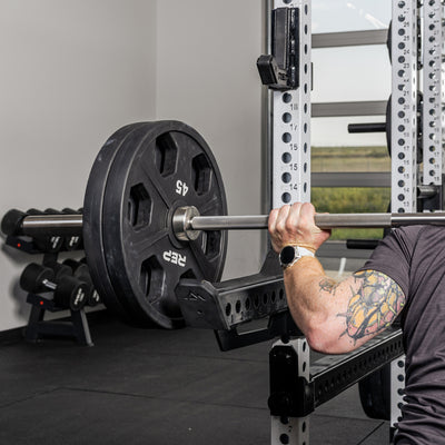 Athlete back squatting with the standard Spotter Arms 2.0 as safeties