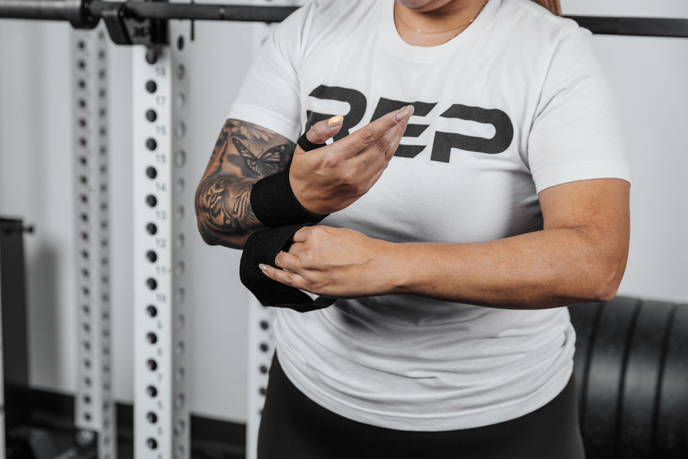 Close up shot of an athlete securing the hook and loop closure of the REP Wrist Wrap around their wrist for a secure fit