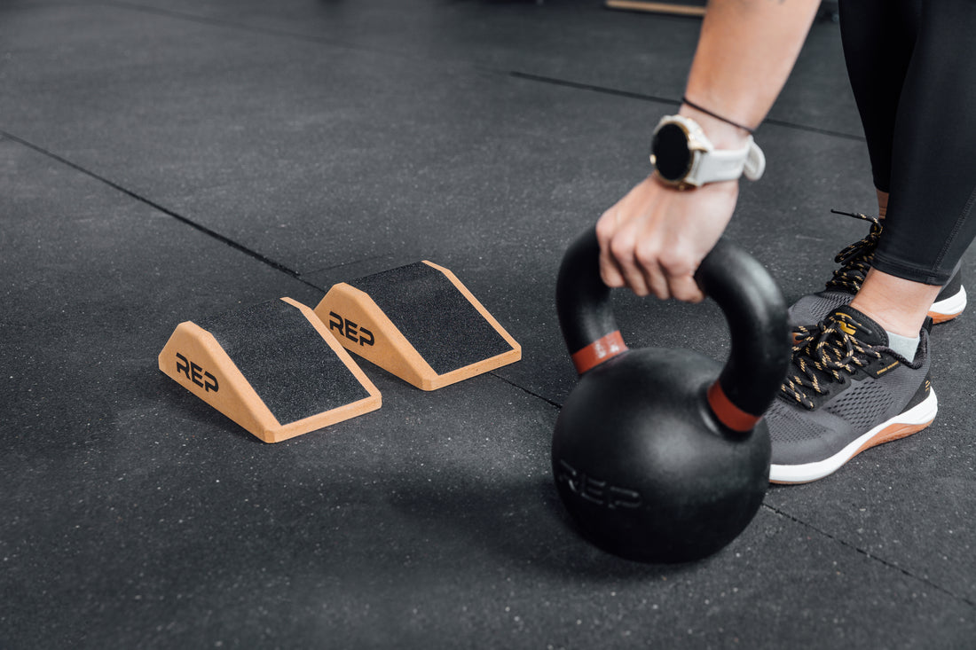 Athlete lifting a kettlebell next to Cork Squat Wedges