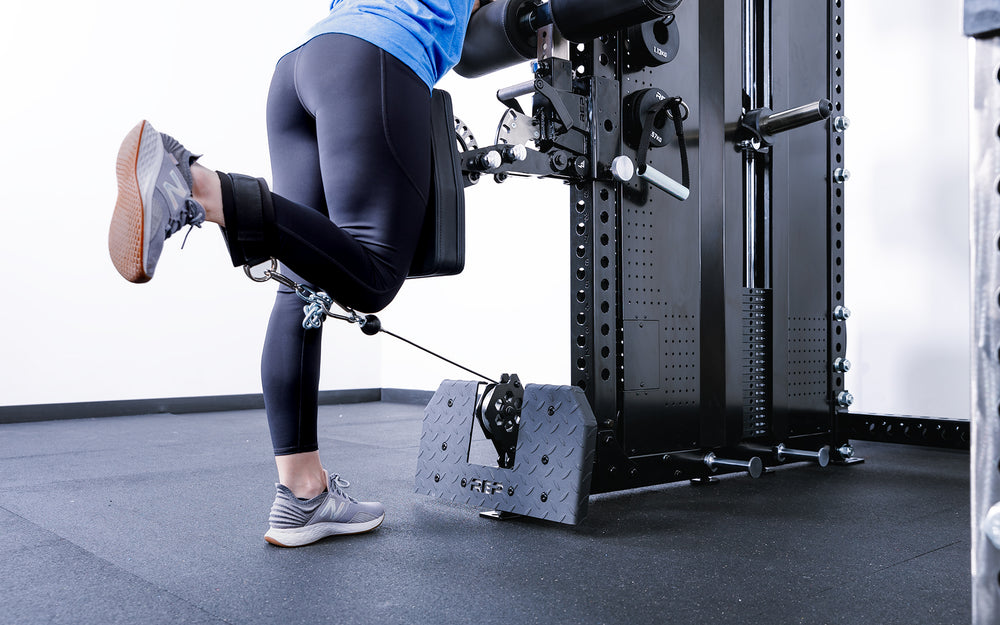 Woman doing leg curls using low row cable and Pegasus Attachment on the Adonis