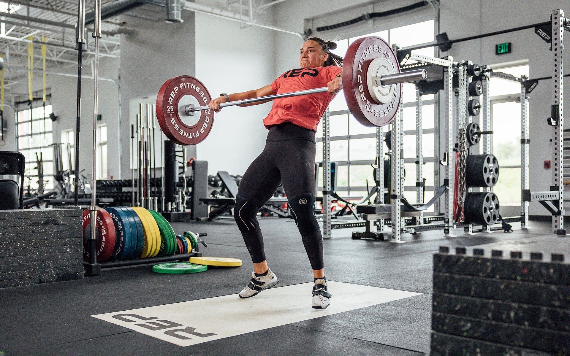 Female lifter performing a snatch on an Olympic lifting platform using REP's 15kg Alpine Weightlifting Bar.