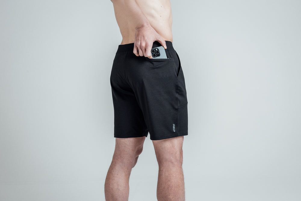Close-up shot of an athlete putting his phone in the zipper pocket of REP’s Men’s Apollo Shorts