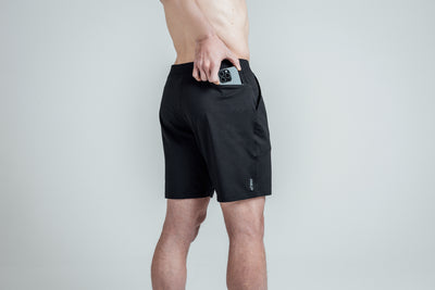 Close-up shot of an athlete putting his phone in the zipper pocket of REP’s Men’s Apollo Shorts in 
Heather Black/Cool Gray