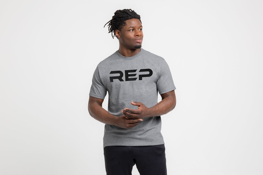 The REP Fitness Men's Bulk Up Heavyweight Crew T-Shirt in Heather Gray/Black front, hands clasped