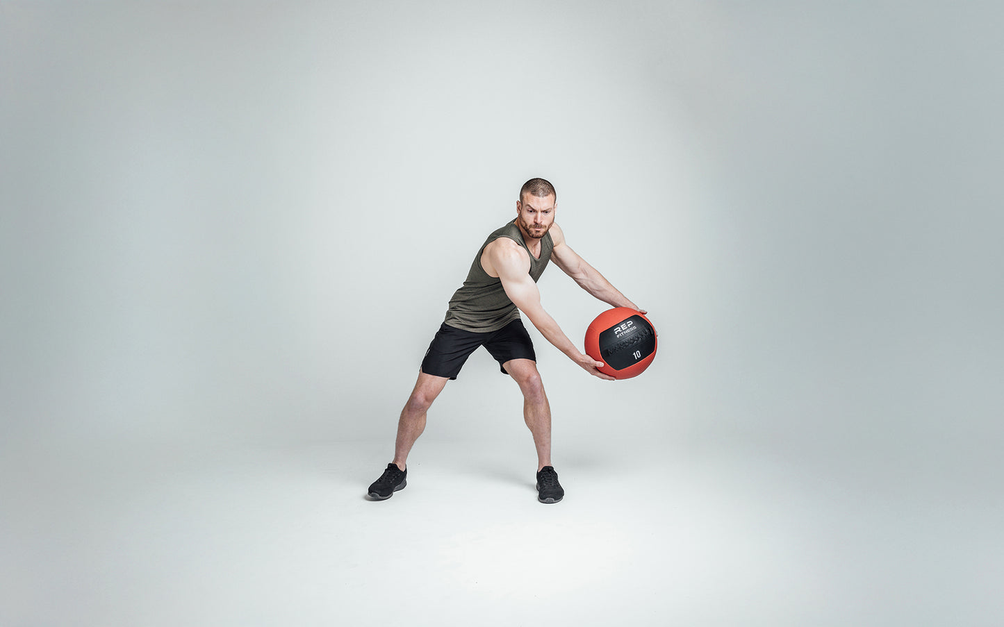 Athlete wearing Black Men's Motus Shorts holding a med ball
