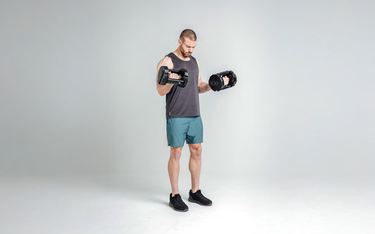 Men's Shorts - Man performing dumbbell curls with adjustable dumbbells and REP® apparel on with a gray background