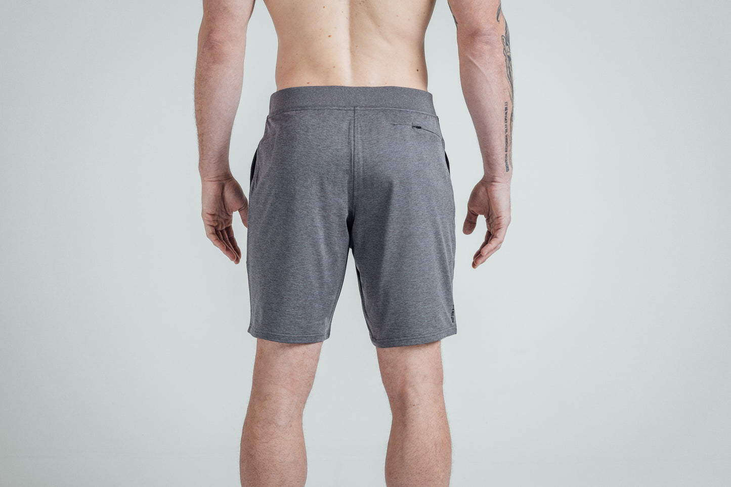 A close-up shot of the rear of REP’s Men’s Apollo Shorts with a 9 inch inseam in Heather Cool Gray/Black on a shirtless athlete. You can see the high-zip zipper pocket and the Smooth, Non-Scrunch Waistband.