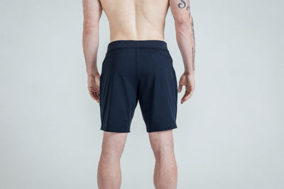 A close-up shot of the rear of REP’s Men’s Apollo Shorts with a 9 inch inseam in Heather Navy/Cool Gray on a shirtless athlete. You can see the high-zip zipper pocket and the Smooth, Non-Scrunch Waistband.