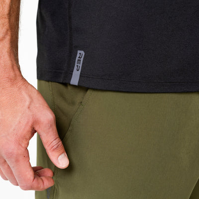 Person wearing a black Men's Aerix shirt with a visible brand logo on the side and green shorts.