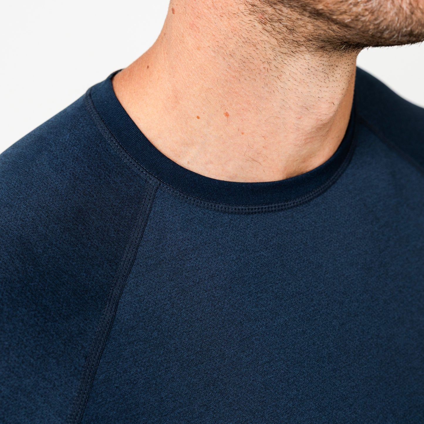 Close-up of a person wearing a navy Men's Aerix shirt on a white background.