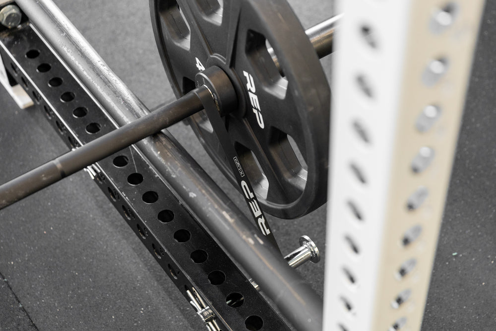 Close-up view of a barbell loaded with a 45lb plate and a black short resistance band for added resistance.