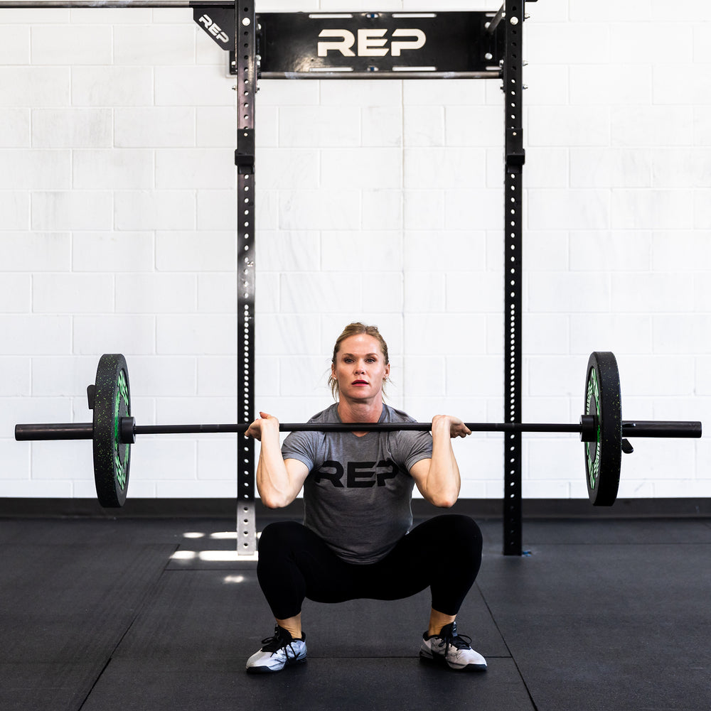 Female lifter in the bottom of a front squat with a loaded REP 15kg Colorado Bar.