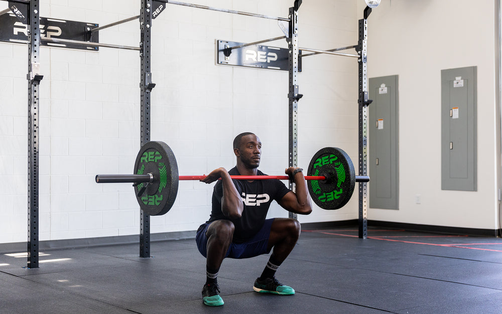 Male lifter in the bottom of a front squat with a loaded REP 20kg Colorado Bar.