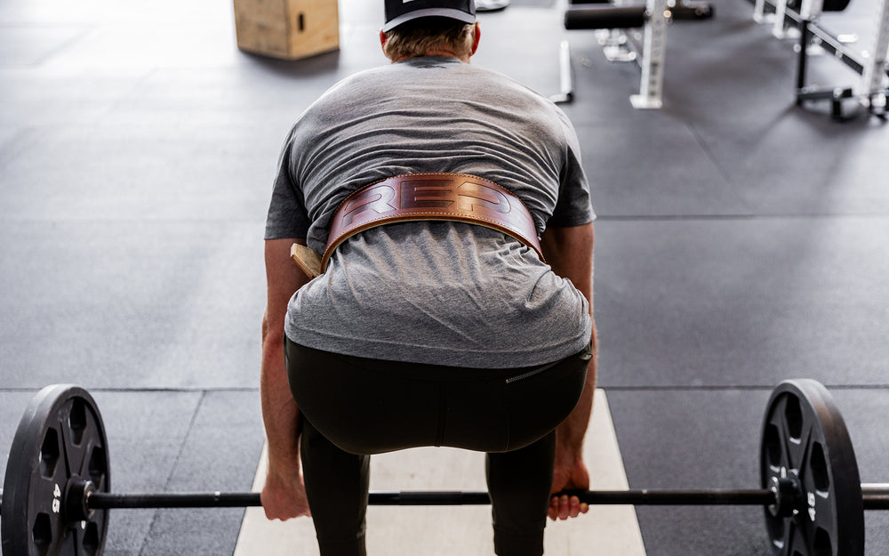 Athlete preparing to perform a deadlift while wearing a brown REP Premium Leather Lifting Belt.