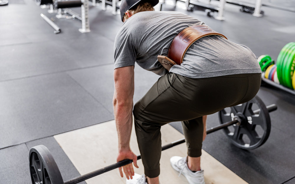 Athlete preparing to perform a deadlift while wearing a brown REP Premium Leather Lifting Belt.