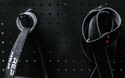 Close up of accessories hanging on pegboard storage hooks.