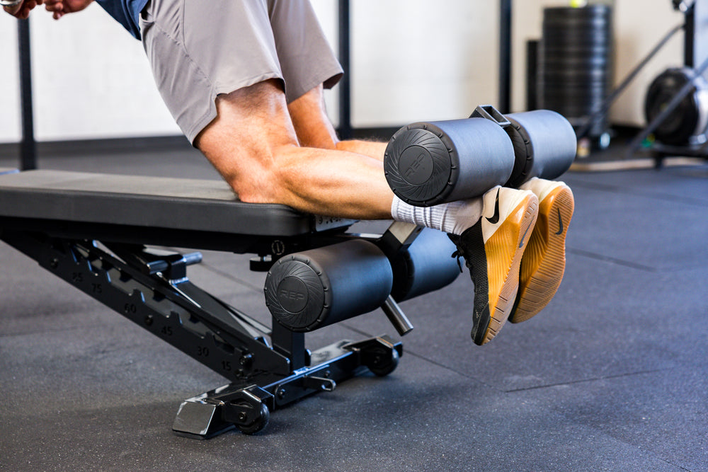 Athlete doing Nordic Hamstring curls with the Adjustable Bench Leg Roller Attachment 2.0