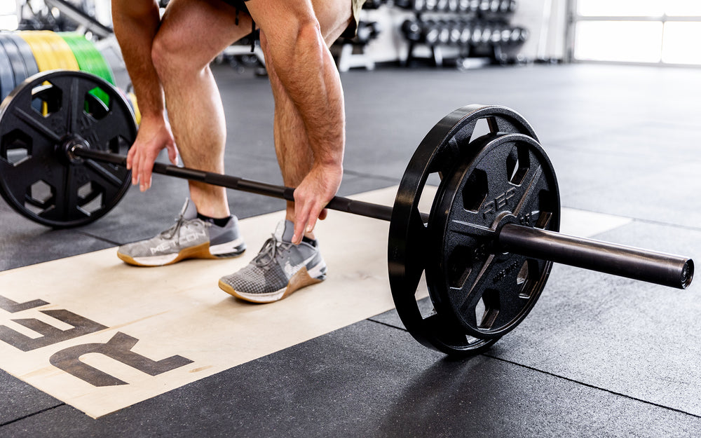 Lifter getting ready to perform a deadlift with a barbell loaded with a pair of 45lb and 25lb USA-Made Equalizer Iron Plates.