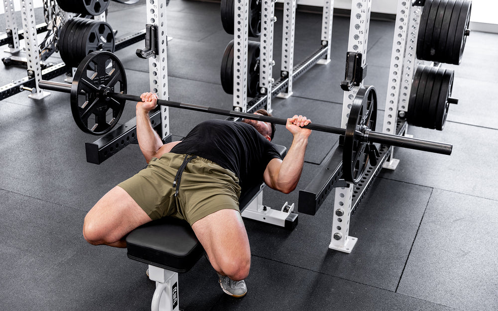 Lifter performing a bench press with a barbell loaded with a pair of 45lb USA-Made Equalizer Iron Plates.