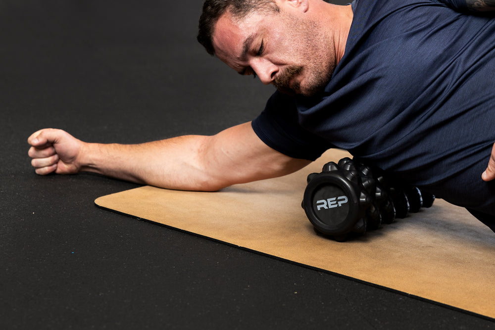 Man using High Density Foam Roller to roll out lats on a cork yoga mat