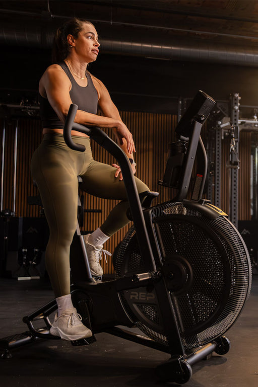 New Products - Woman exercising on the REP® Strive™ air bike for cardio in a gym setting